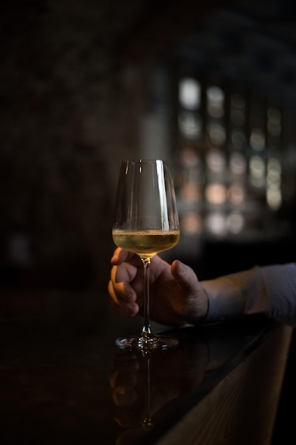 Gekapte afbeelding van een man met een hand die een wijnglas vasthoudt bij de bar.