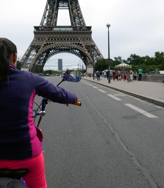 Foto gekapte afbeelding van een meisje op de fiets voor de eiffeltoren