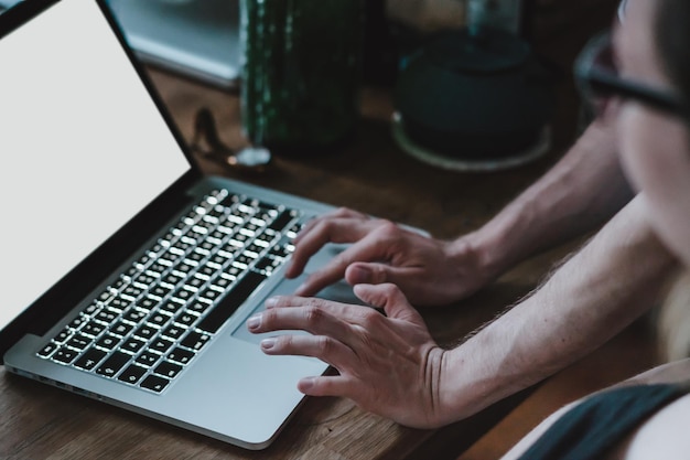 Gekapte afbeelding van een persoon die een laptop op het bureau gebruikt.