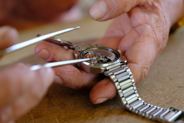 Gekapte afbeelding van een persoon die een polshorloge op tafel repareert
