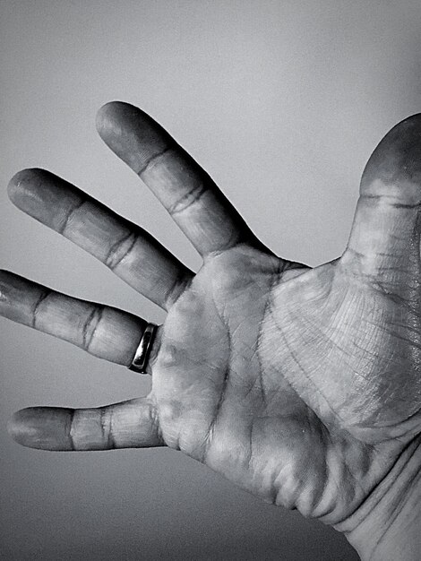 Foto gekapte afbeelding van een persoon met een handpalm op een grijze achtergrond