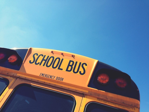 Gekapte afbeelding van een schoolbus tegen een blauwe lucht