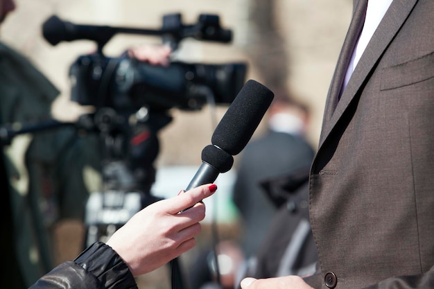 Foto gekapte afbeelding van een verslaggever die een microfoon vasthoudt tijdens het geven van een interview