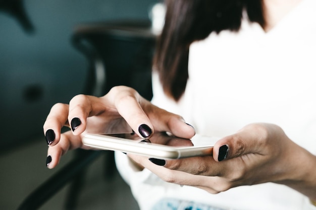 Gekapte afbeelding van een vrouw die een mobiele telefoon gebruikt