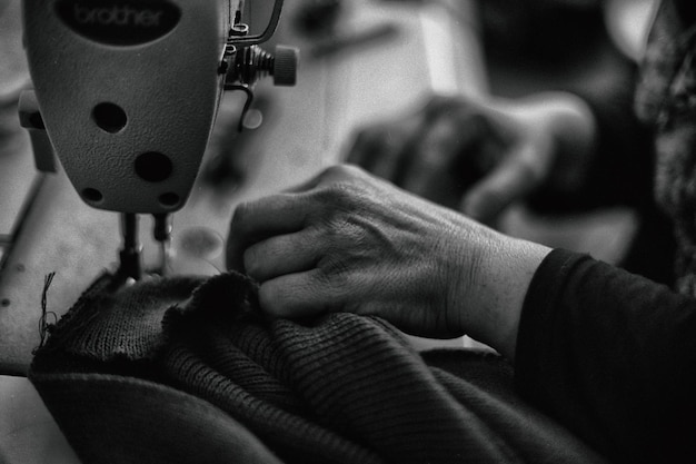 Gekapte afbeelding van een vrouw die thuis een naaimachine gebruikt