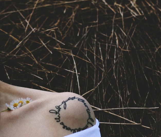 Foto gekapte afbeelding van een vrouw met een tatoeage op de schouder tegen planten