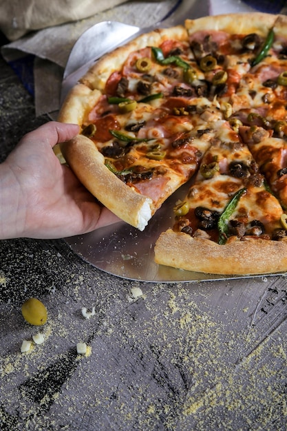 Gekapte afbeelding van een vrouwelijke hand die pizza eet aan tafel