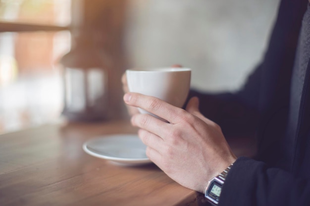 Gekapte afbeelding van een zakenman die koffie drinkt terwijl hij aan tafel zit