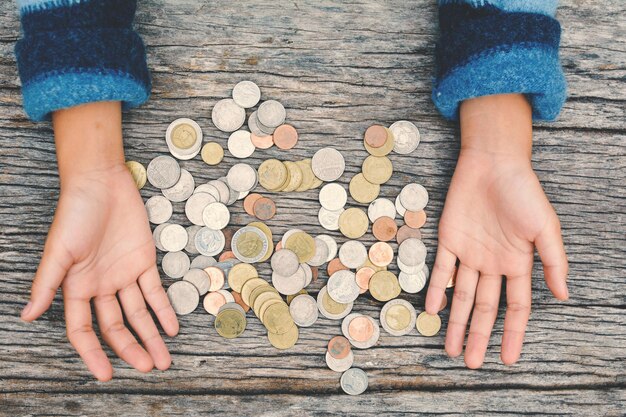 Foto gekapte afbeelding van iemands handen door munten aan een houten tafel