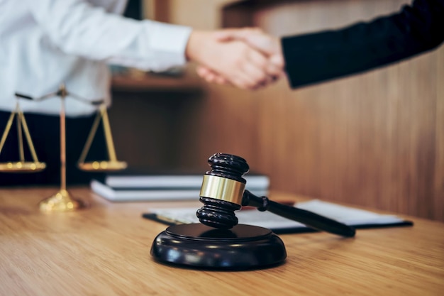 Gekapte afbeelding van rechter en cliënt die elkaar de hand schudden met een hamer op tafel