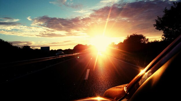 Foto gekapte auto op de weg tegen de heldere zon bij zonsondergang