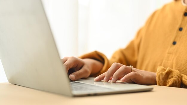 Gekapte foto van een jonge vrouw in casual kleding die thuis aan een laptop werkt.