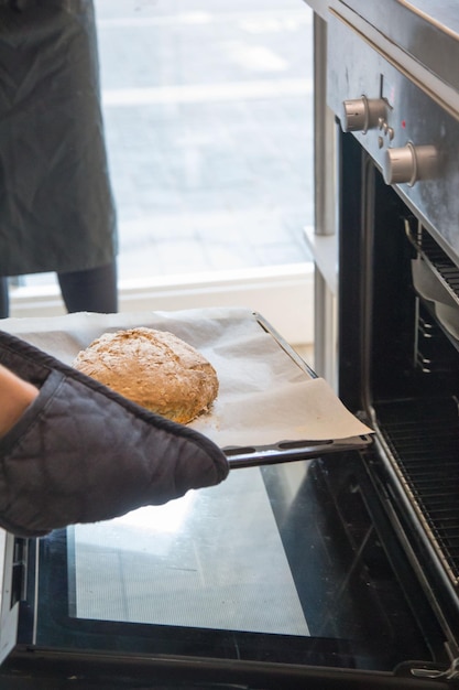 Foto gekapte hand die brood in de oven stopt