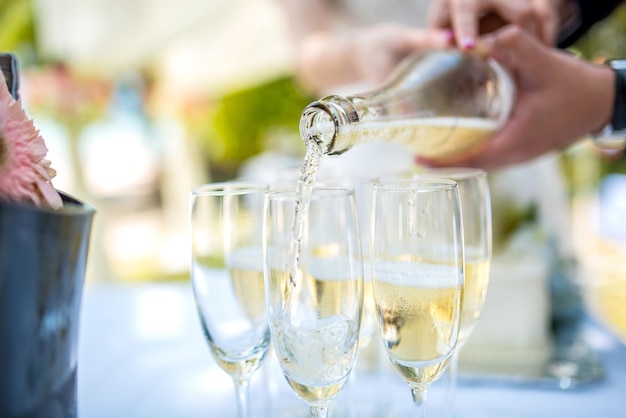 Gekapte hand die champagne in een fluit giet.