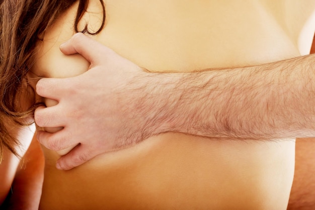 Foto gekapte hand die de borst van een naakte vrouw grijpt.