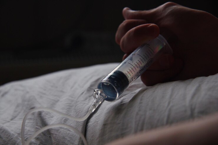 Foto gekapte hand die de injectiespuit op het bed houdt