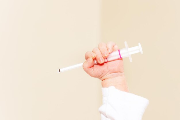 Gekapte hand die de spuit vasthoudt tegen een witte achtergrond