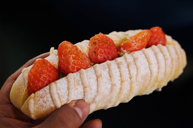 Foto gekapte hand die een burger vasthoudt op een zwarte achtergrond