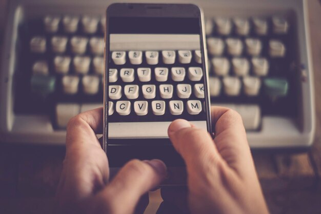 Foto gekapte hand die een schrijfmachine fotografeert met een smartphone