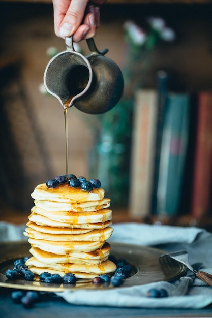 Gekapte hand die honing op pannenkoek giet