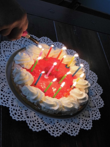 Gekapte hand die kaarsen aansteekt op verjaardagstaart