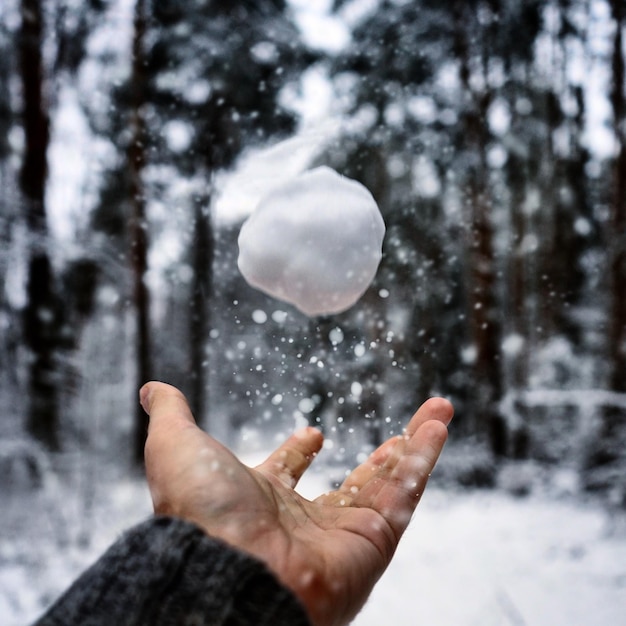 Foto gekapte hand die met sneeuw speelt.