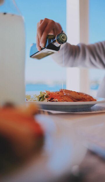 Foto gekapte hand die olie op salade giet