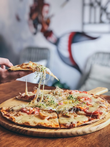 Gekapte hand die pizza vasthoudt aan tafel