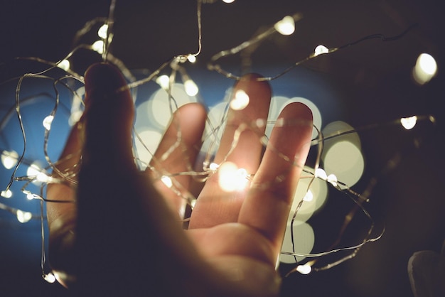 Foto gekapte hand die's nachts verlichte strijklichten vasthoudt