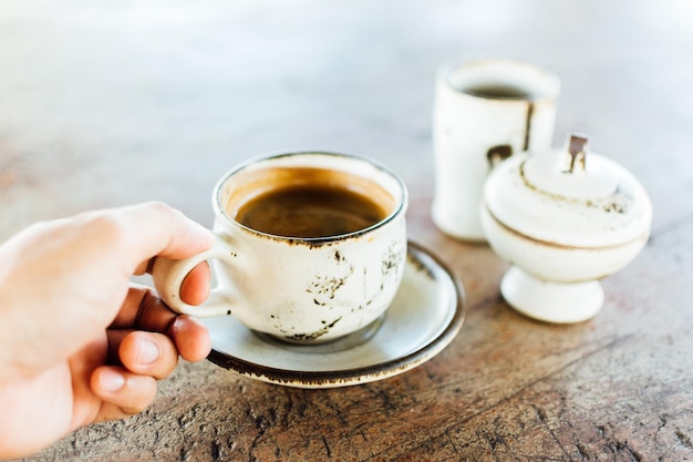 Gekapte hand met een verse espresso-beker op tafel