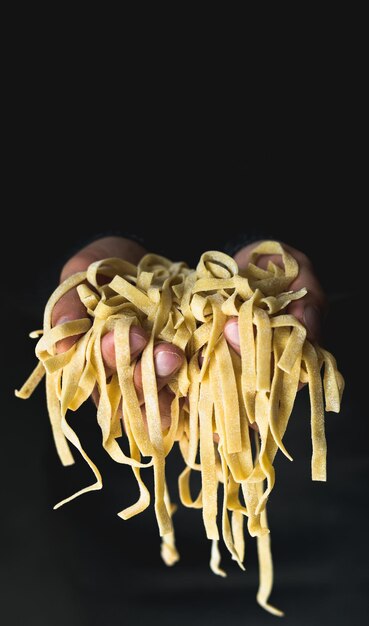 Foto gekapte hand met pasta tegen een zwarte achtergrond