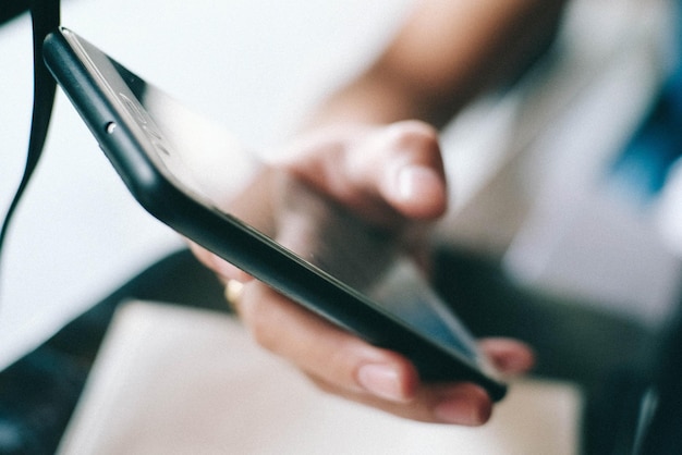 Foto gekapte hand met telefoon aan tafel