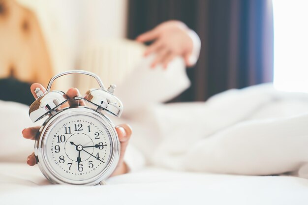 Foto gekapte hand met wekker op bed thuis