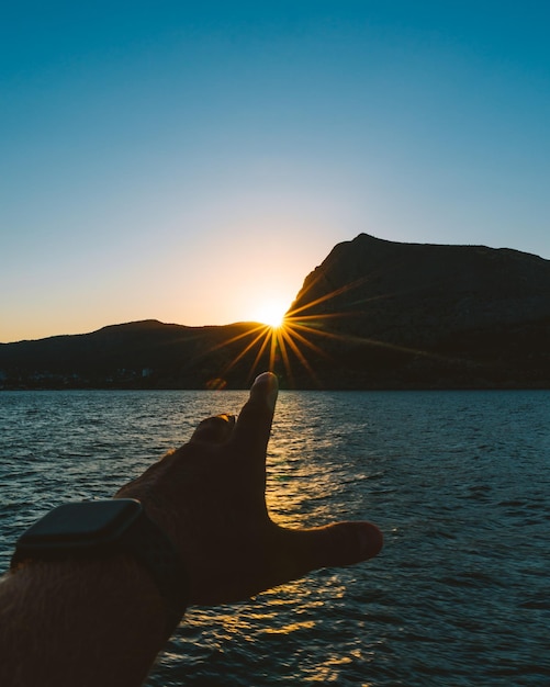 Gekapte hand tegen de zee bij zonsondergang