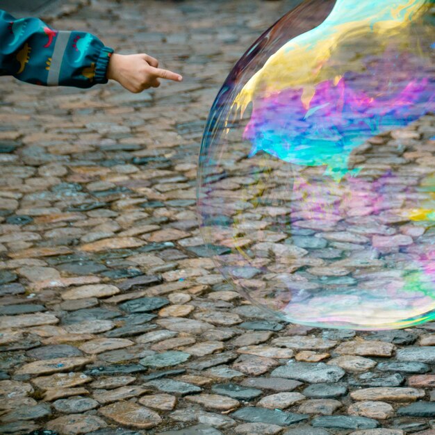 Foto gekapte hand van een kind dat op een bubbel op een voetpad wijst