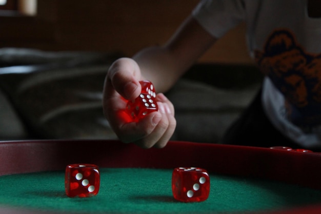 Gekapte hand van een kind met rode dobbelstenen over de tafel