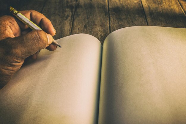 Foto gekapte hand van een man die in een leeg boek schrijft