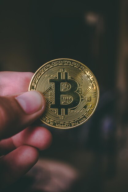 Gekapte hand van een persoon die bitcoin vasthoudt in de donkere kamer