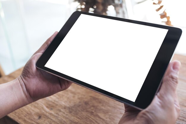 Foto gekapte hand van een persoon die een digitale tablet boven de tafel houdt