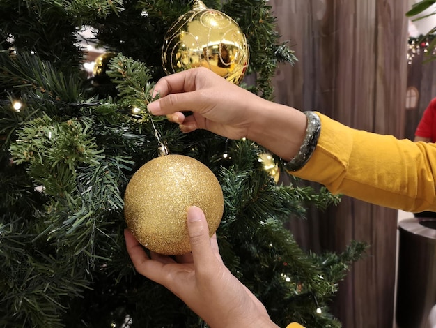 Foto gekapte hand van een vrouw die een kerstboom versiert