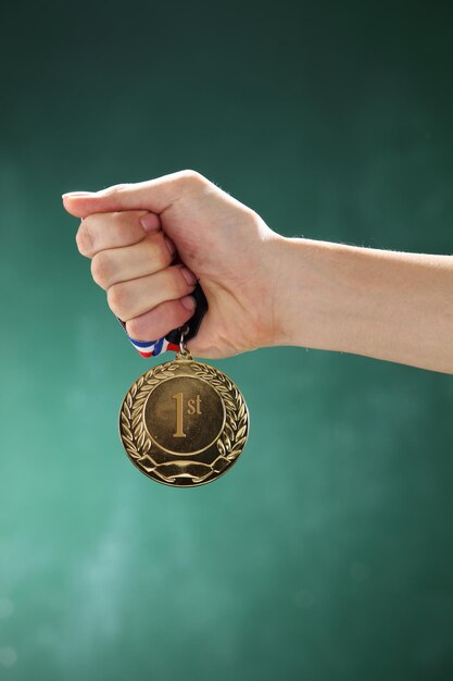 Gekapte hand van een vrouw die een medaille tegen de muur houdt