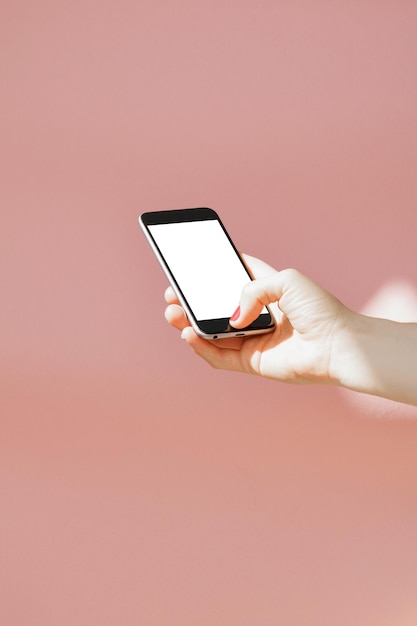 Gekapte hand van een vrouw die een mobiele telefoon gebruikt op een gekleurde achtergrond
