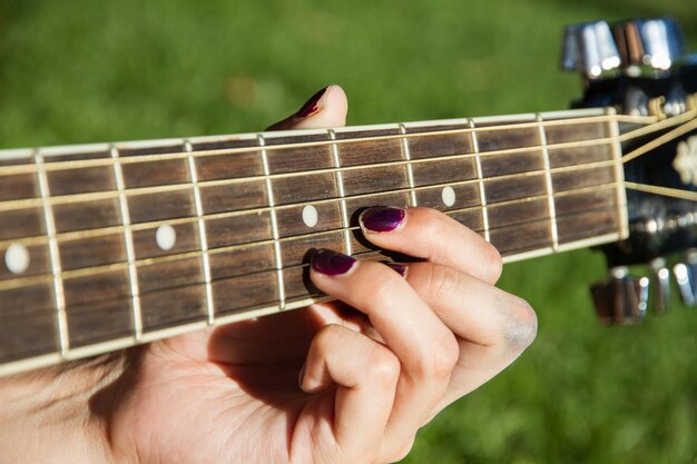 Foto gekapte hand van een vrouw die gitaar speelt in een openbaar park