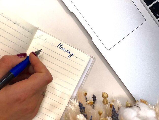 Foto gekapte hand van een vrouw die in een boek op tafel schrijft