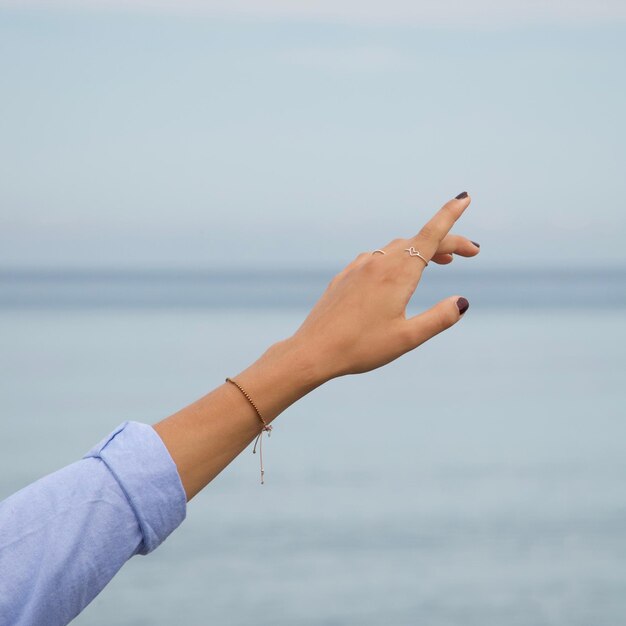 Foto gekapte hand van een vrouw tegen de zee