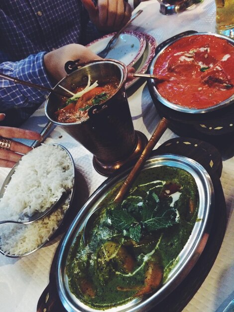 Foto gekapte hand van mensen die indiase eten eten in een restaurant