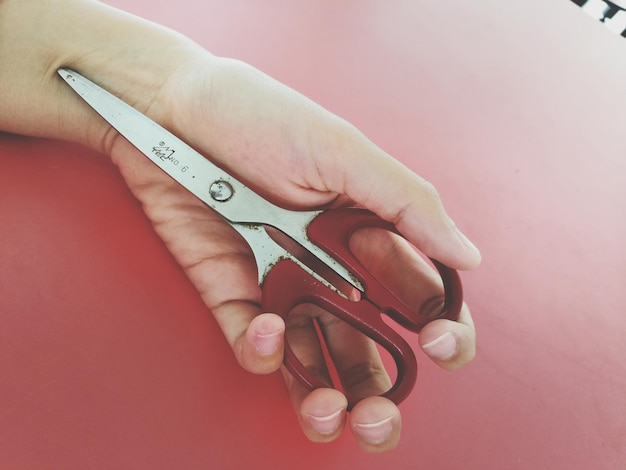 Foto gekapte hand van vrouw met schaar op tafel