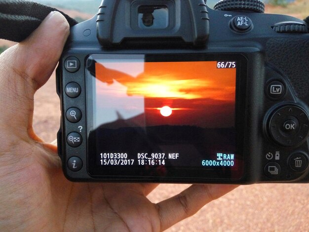 Foto gekapte handcamera met zonsondergangfoto