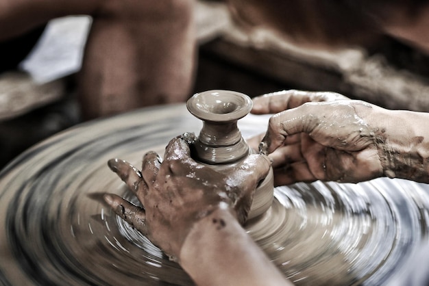 Gekapte handen die aardewerk maken in een werkplaats