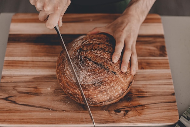 Gekapte handen die brood snijden aan boord.